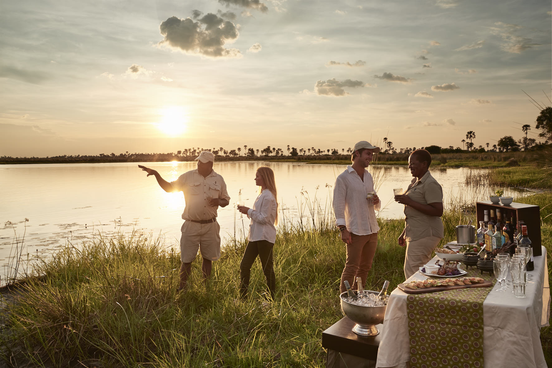 Guests sharing sundowners and conversation with local staff in Botswana 