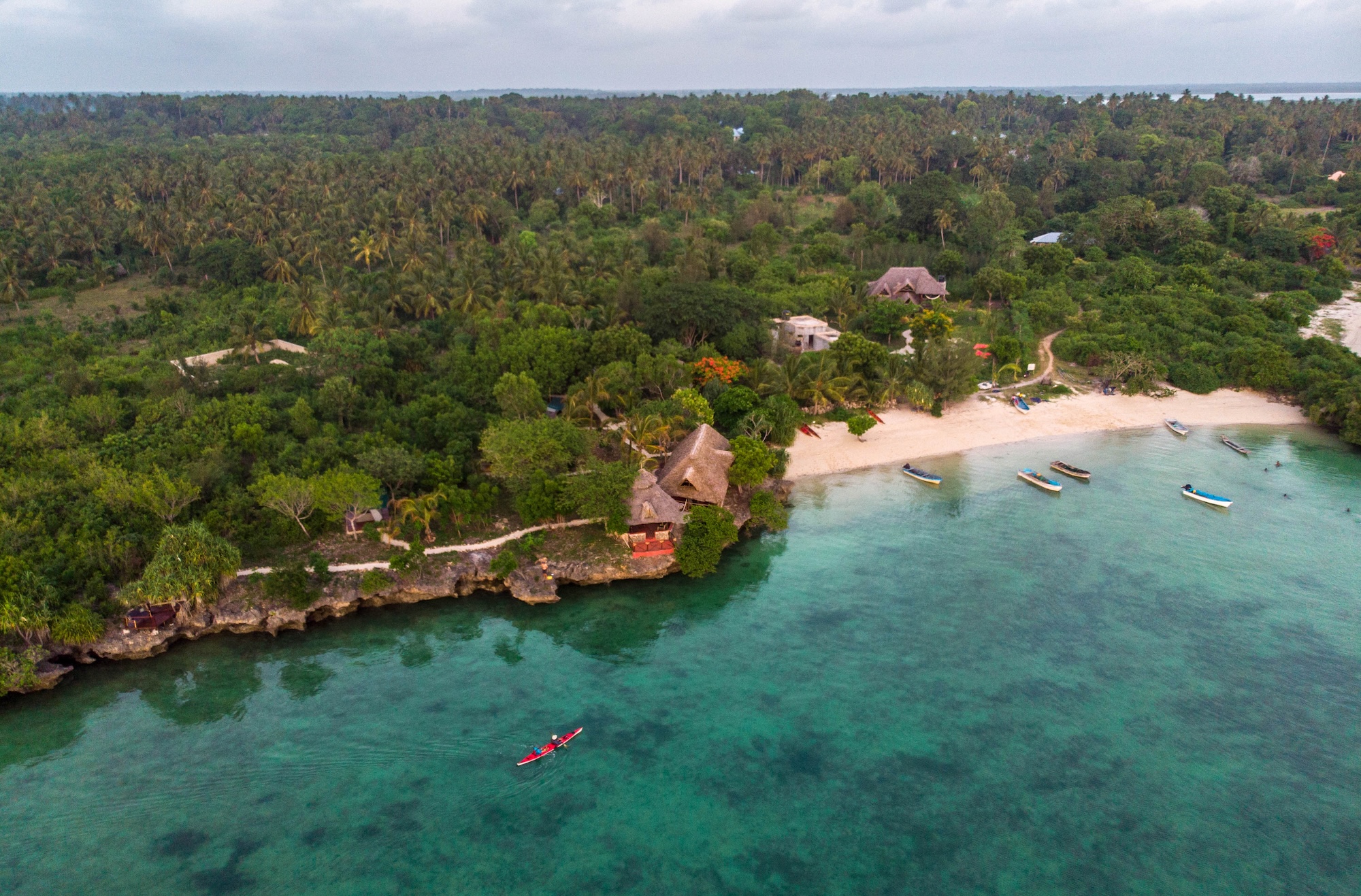 A kayak glides on blue ocean waters towards the shore of Zanzibar, one of the best East Africa holiday destinations.